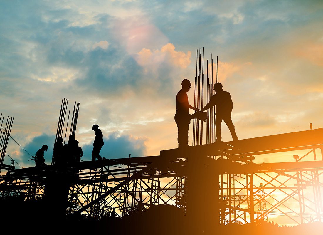 Insurance by Industry - Silhouettes of Contractors Standing on Steel Beams During a Commercial Construction Project at Sunset